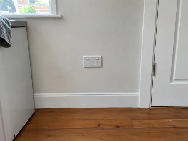 Double power point on a painted wall above skirting beside a doorway and timber floor in Chatswood
